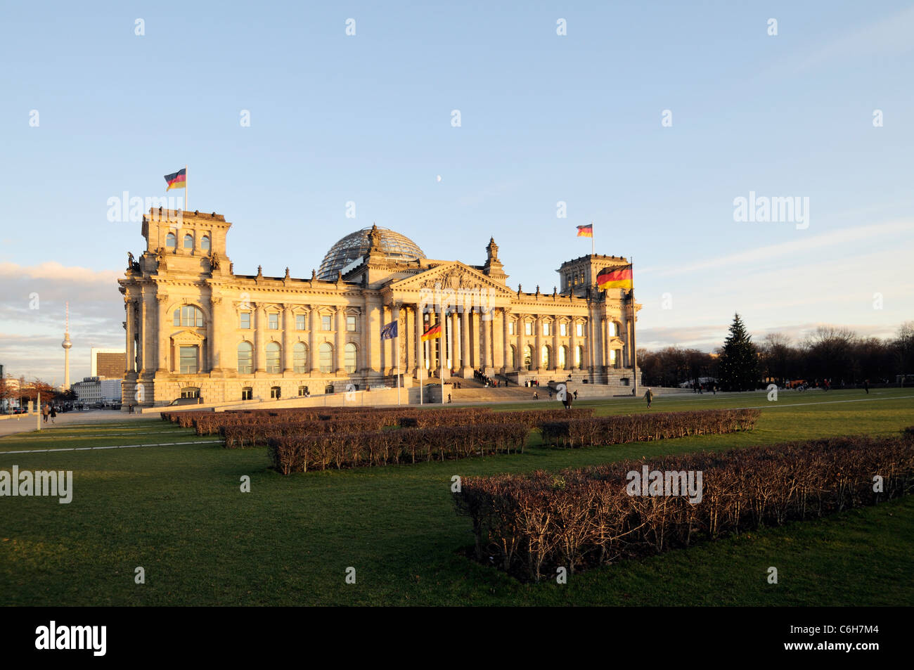 Warm evening sunlight illuminating the mighty Reichstag parliament with clear blue sky and flags flying. Stock Photo