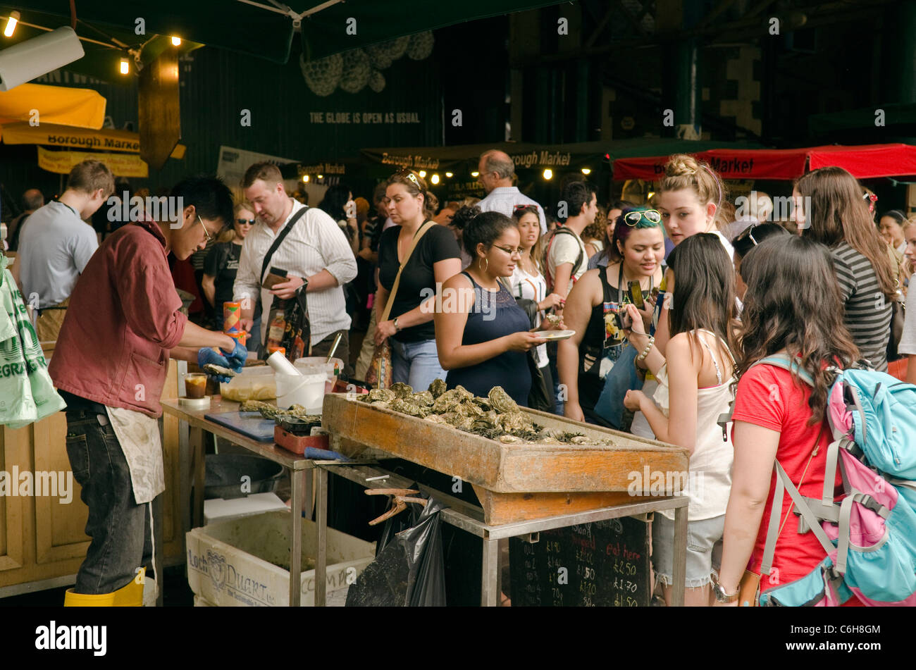 Crowd of people shopping and buying fresh oysters at a Borough Market fresh shellfish stall London SE1 UK Stock Photo