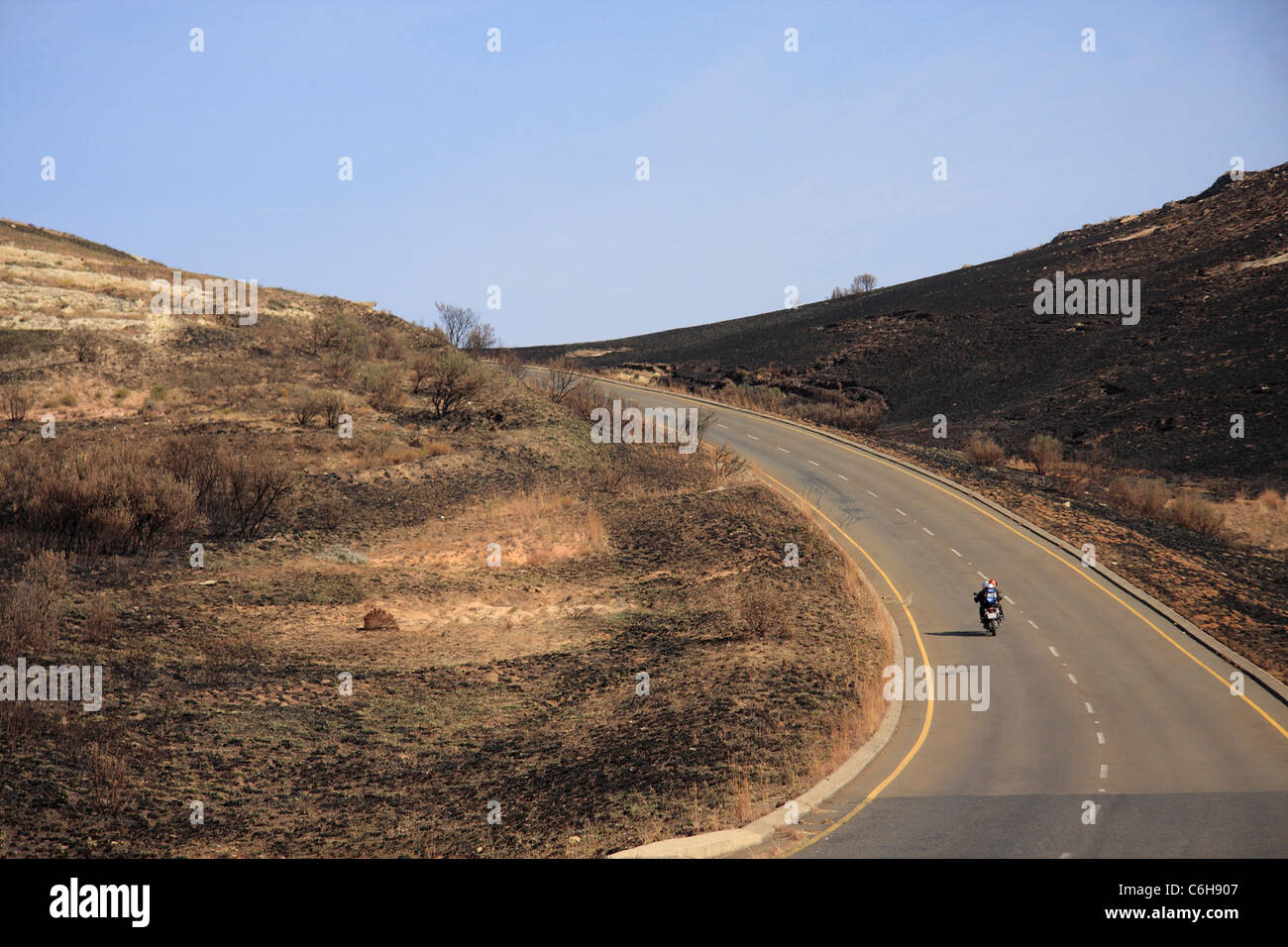 Tar road in remote landscape with motorcycle Stock Photo