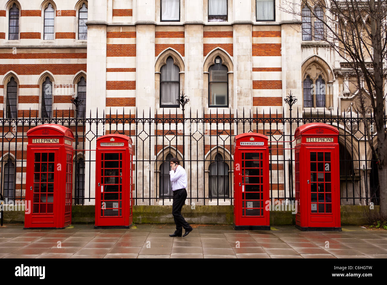 Mobile phone user next to red phone boxes near the High Court, Chancery Lane, London Stock Photo