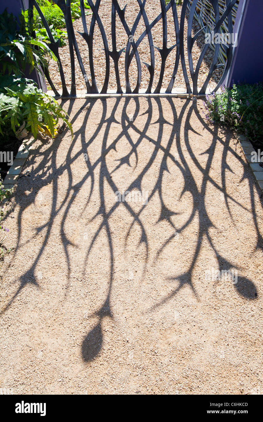 The shadow on a garden gate on a garden path. Stock Photo