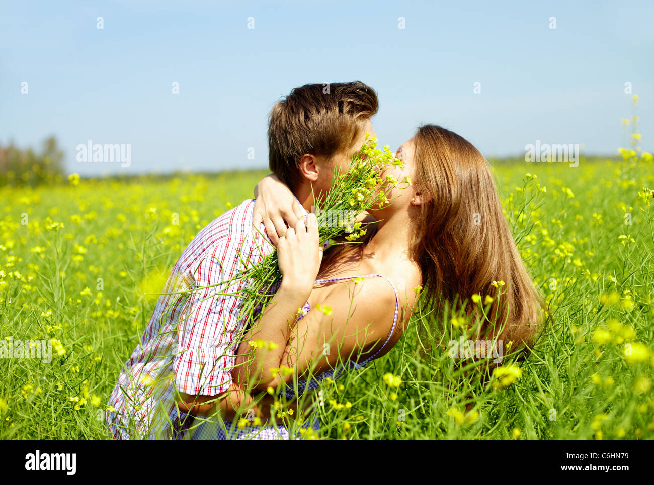 Portrait of young romantic couple embracing one another in flower field ...