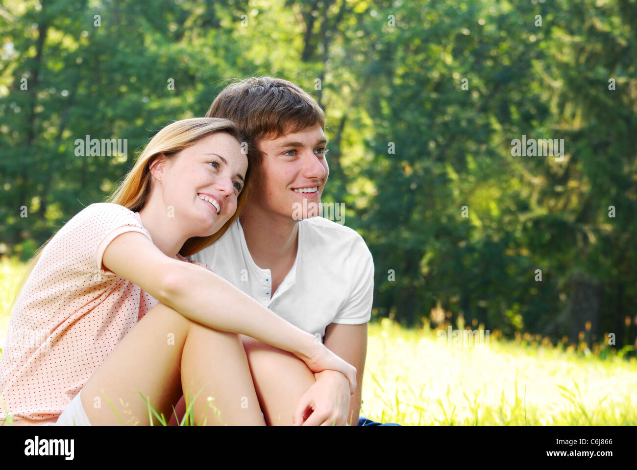 Happy young couple sitting on the grass Stock Photo - Alamy