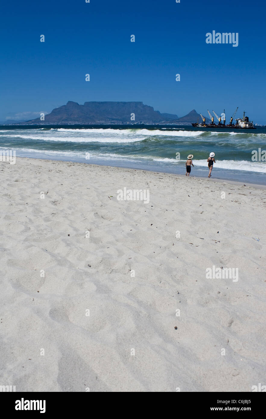 Two children run into the Atlantic Ocean on the beach at Bloubergstrand in Cape Town, South Africa. Stock Photo
