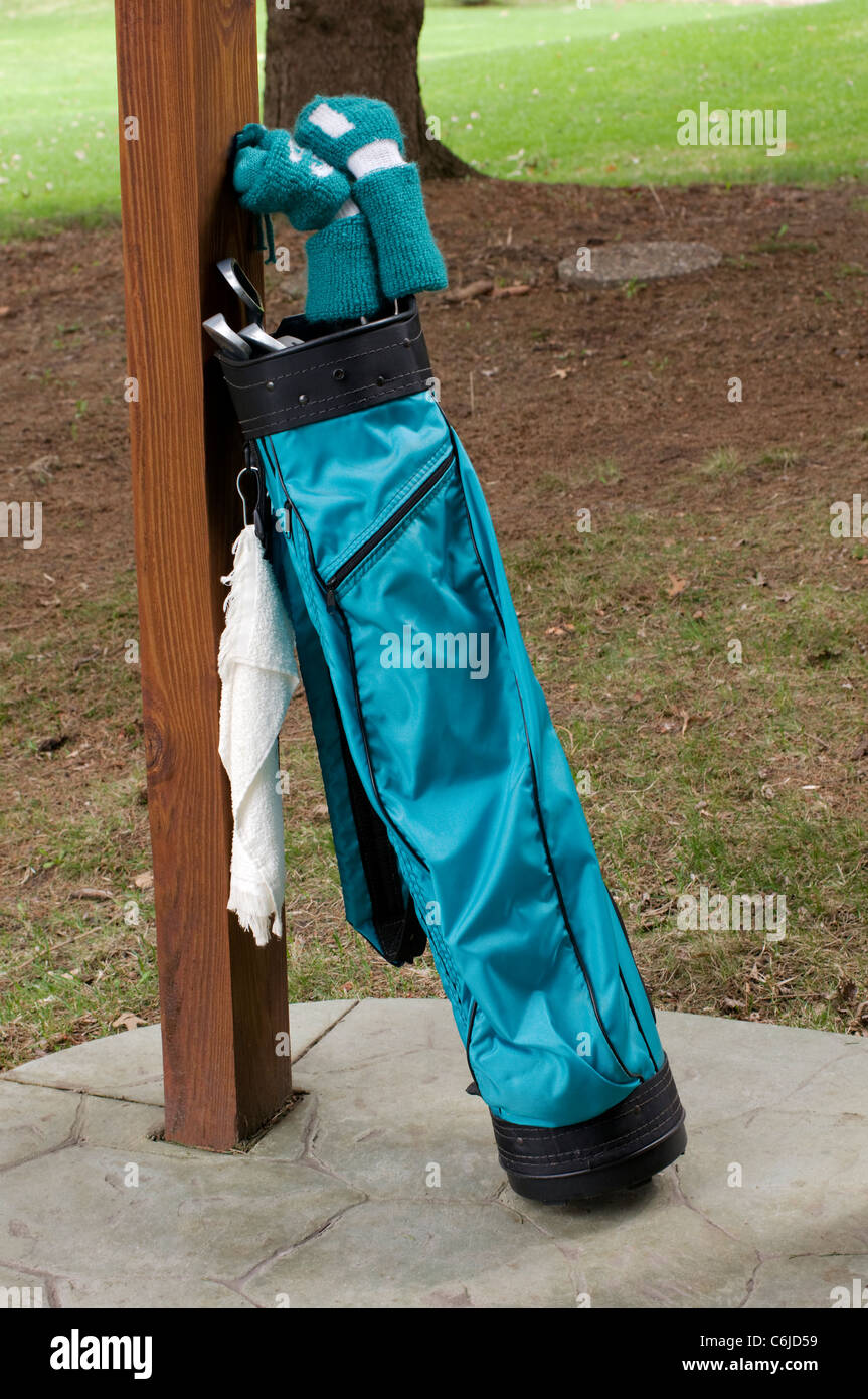 Ladies golf clubs and bag leaning against patio deck support Stock Photo