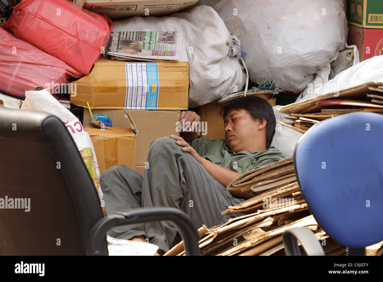 tired asian man sleeping among furniture in removal van in the street, bangkok, thailand Stock Photo