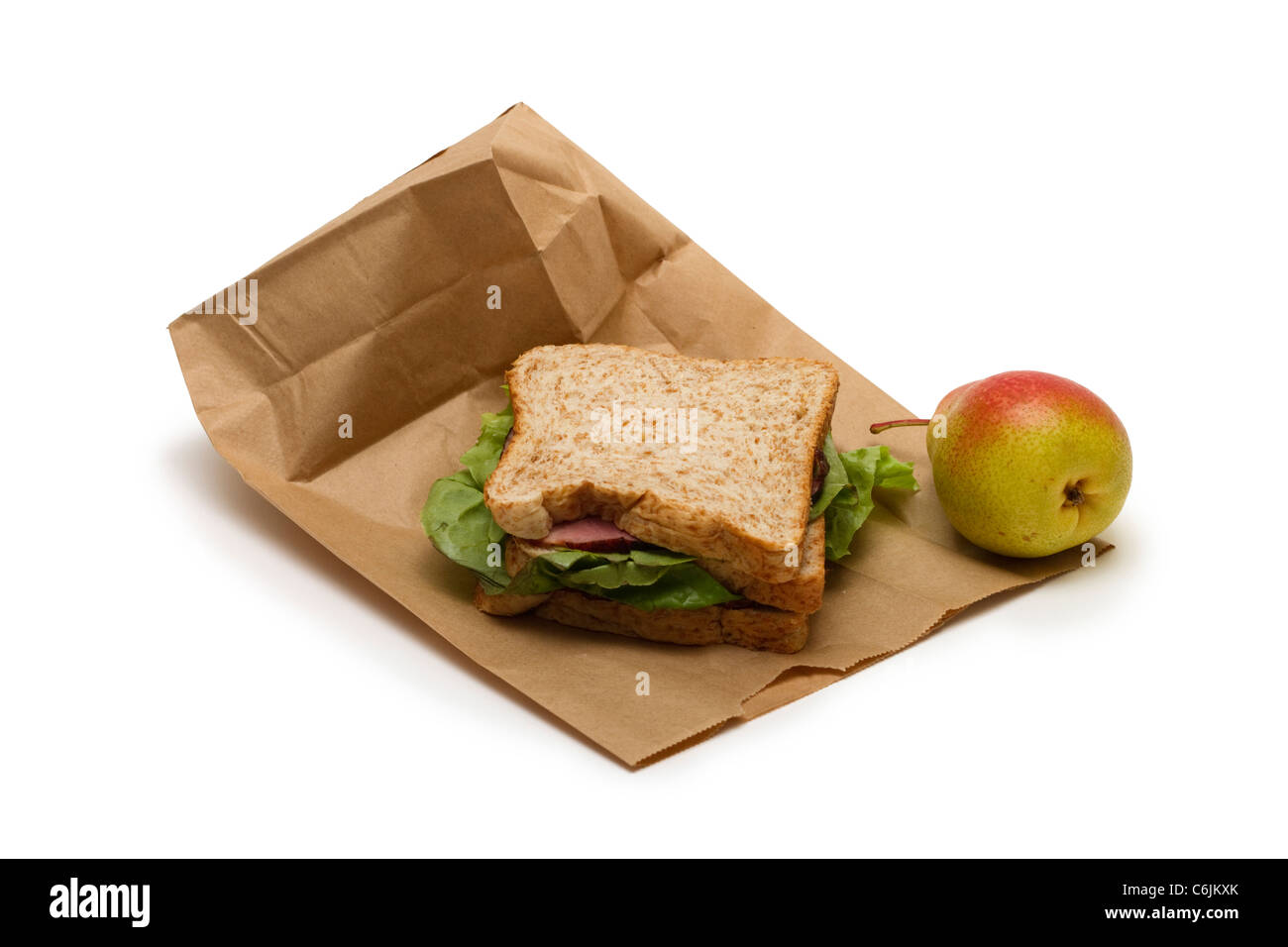Brown bag lunch with ham sandwich and a pear on a white background Stock Photo