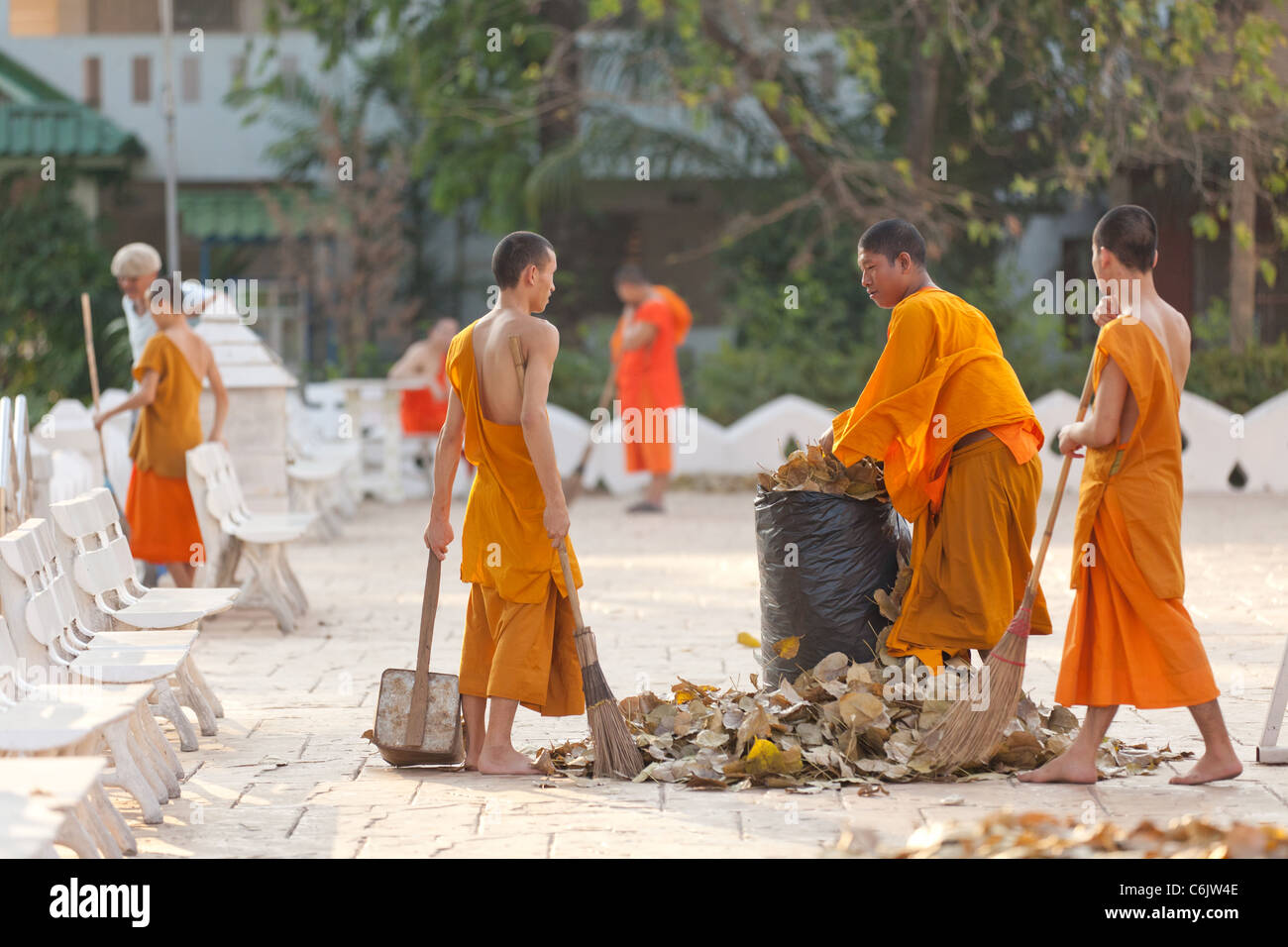 thai buddhist monks sweeping dead leaves in temple square, chiang mai, thailand Stock Photo