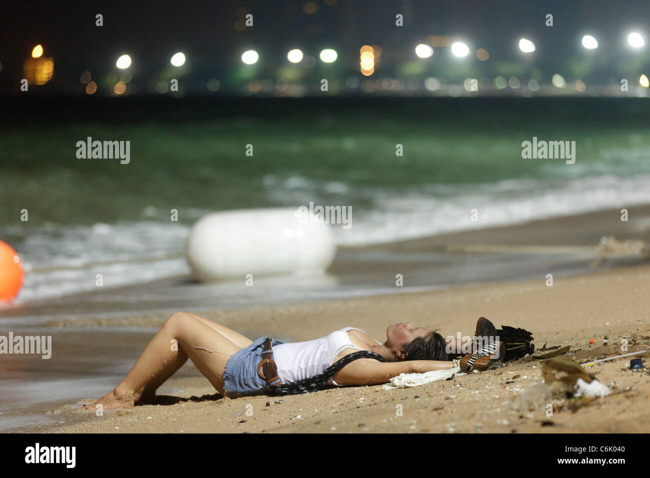thai woman wearing wet clothes lying back on sand in Pattaya beach at