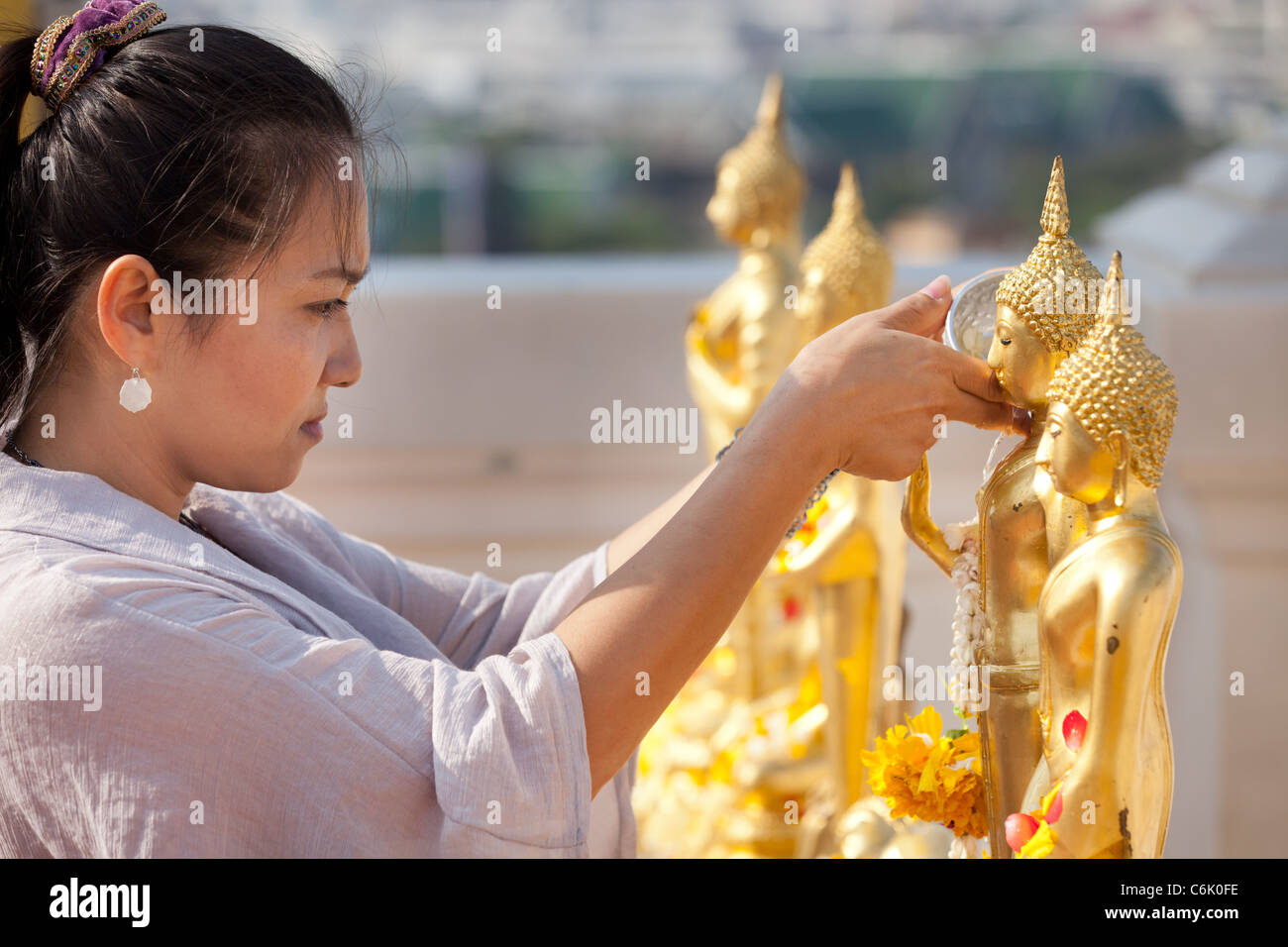 thai woman pouring water on buddha statue for songkran festival