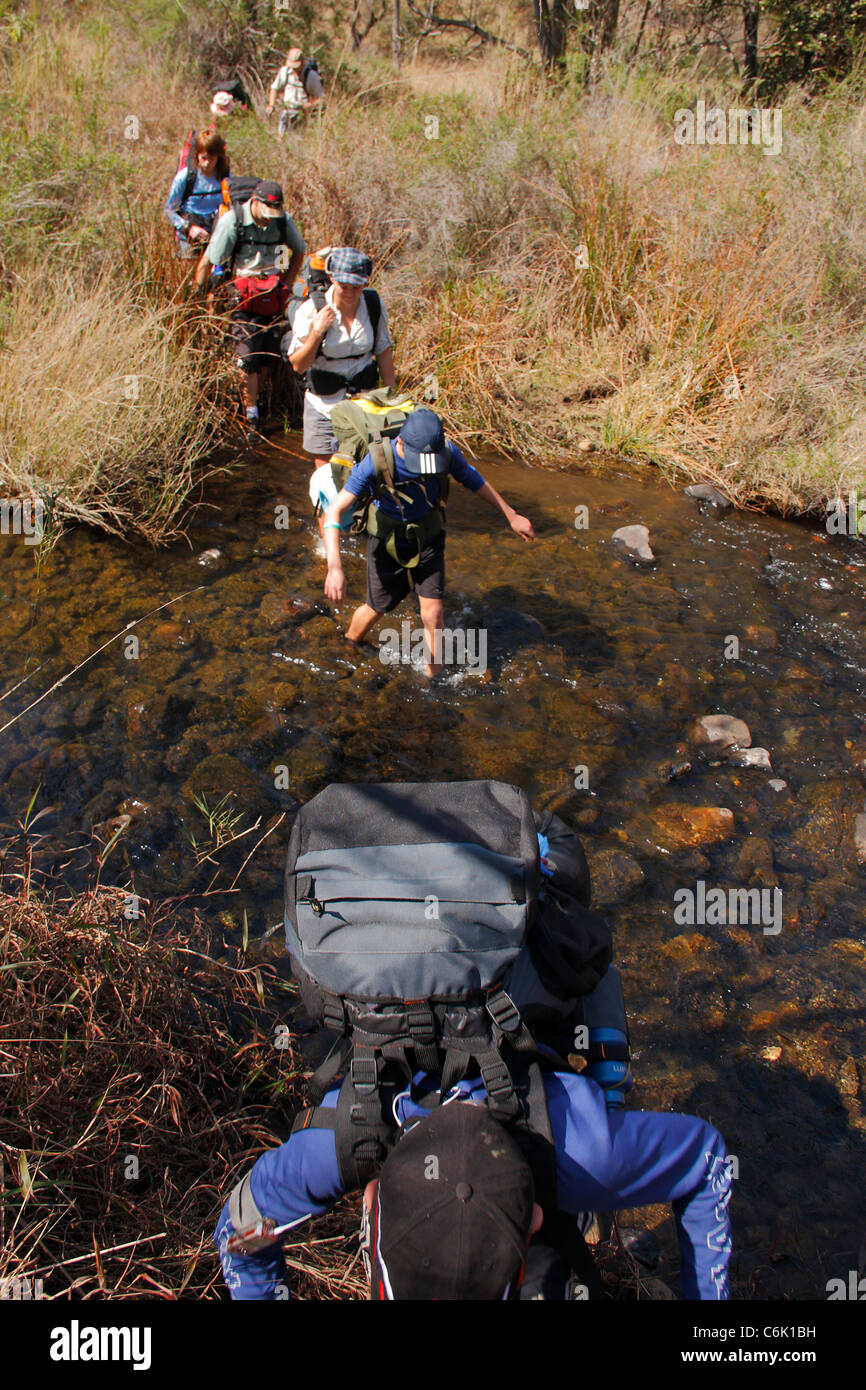 Hikers crossing mountain stream Stock Photo