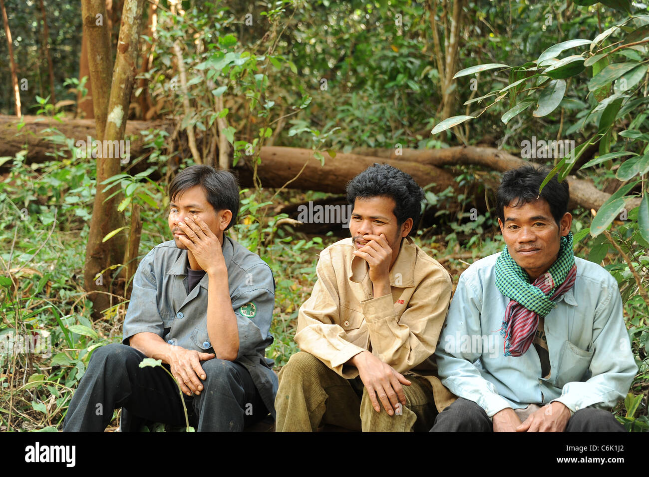 Three mahouts sitting down in the woods in Cambodia Stock Photo