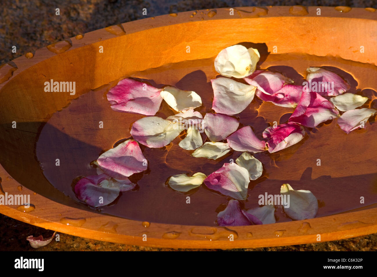 Rose petals floating on water in a wooden bowl Stock Photo Alamy
