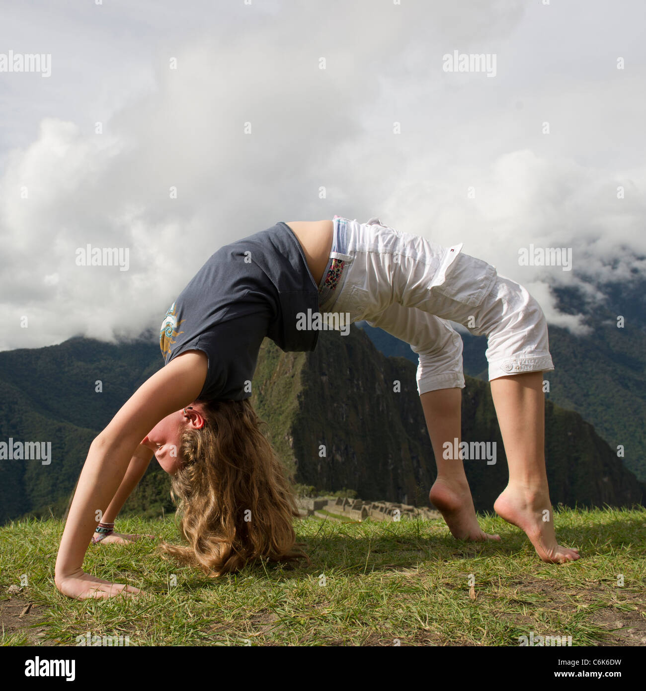 Teenage girl doing wheel pose with valley in the background, The Lost City of The Incas, Machu Picchu, Cusco Region, Peru Stock Photo