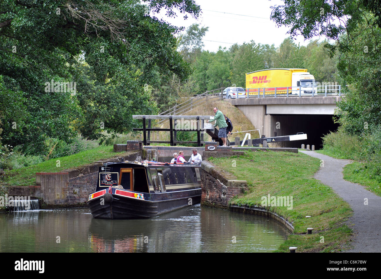 Narrowboat on the Stratford Canal with a DHL lorry on the M40 motorway behind, Warwickshire, UK Stock Photo