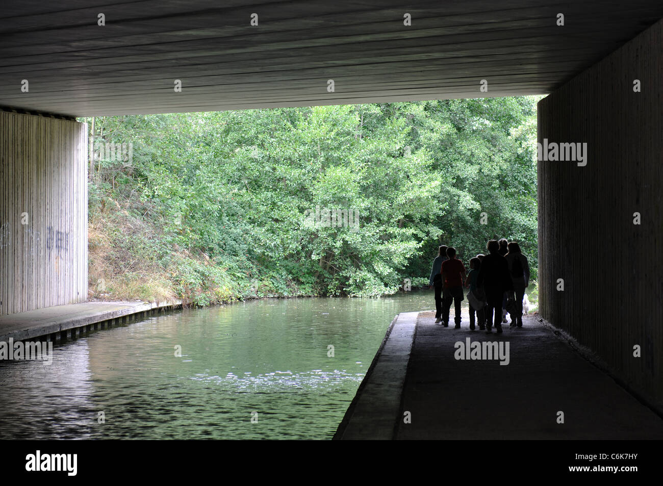 People walking on towpath of Stratford Canal passing under the M40 motorway, Warwickshire, England, UK Stock Photo