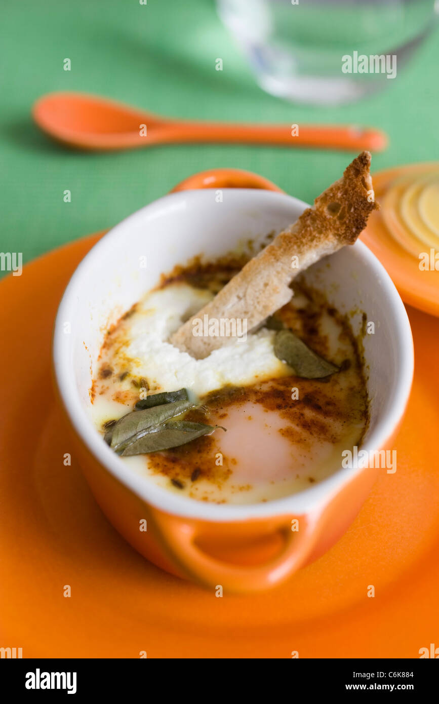 Oeufs en cocotte with herbs and spices, served with sliced bread strip Stock Photo Alamy