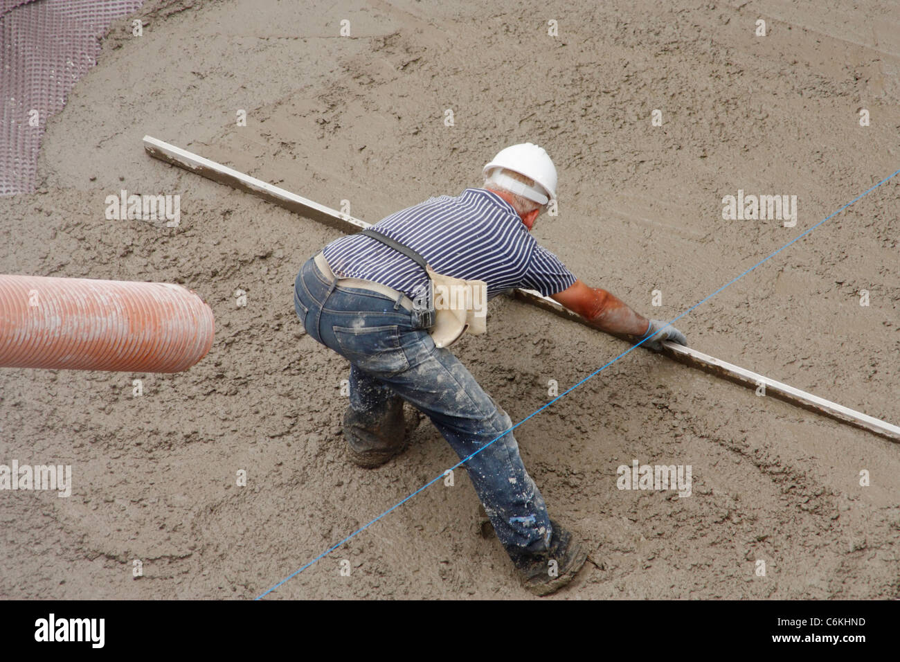 Workman levelling wet concrete on new house foundation in Spain Stock