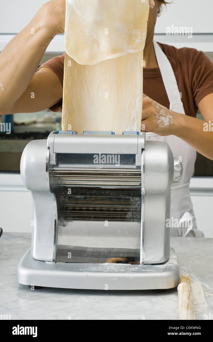 Making lasagna noodles, feeding pasta dough through pasta machine Stock