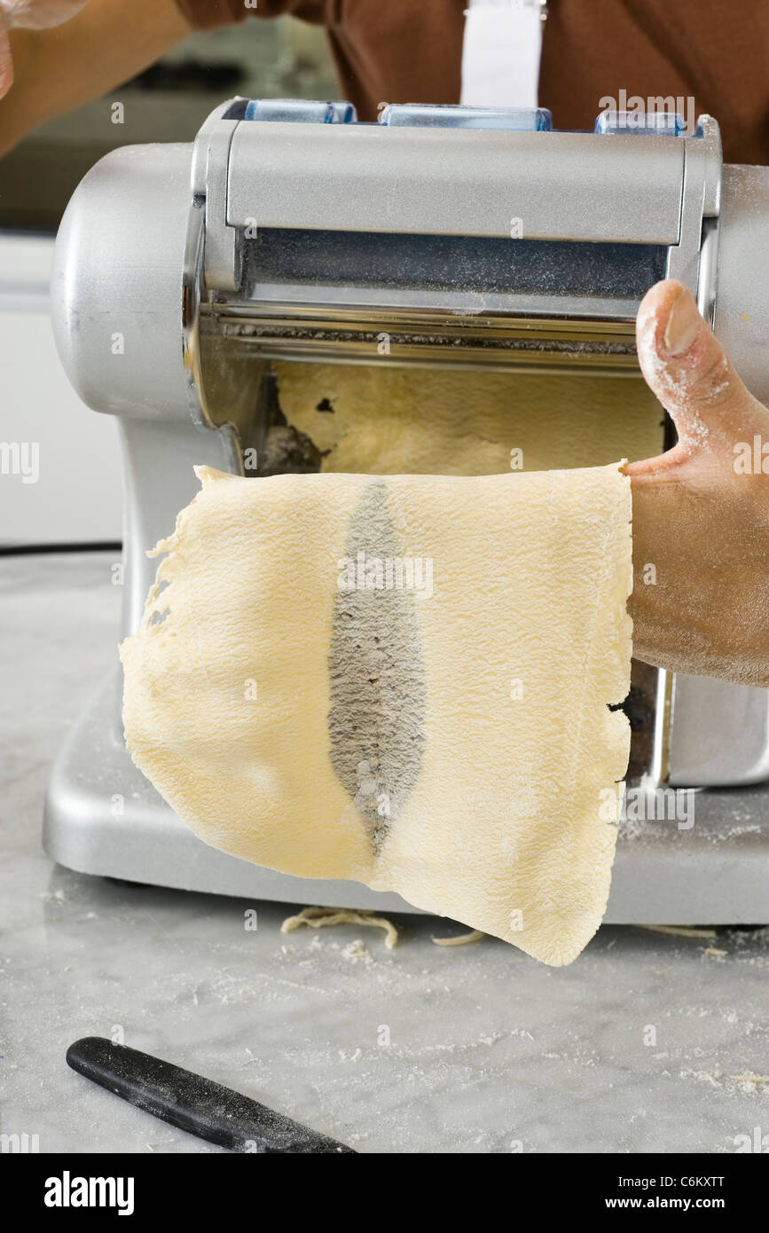 Rolling pasta dough through pasta machine to make pasta sheets Stock Photo Alamy