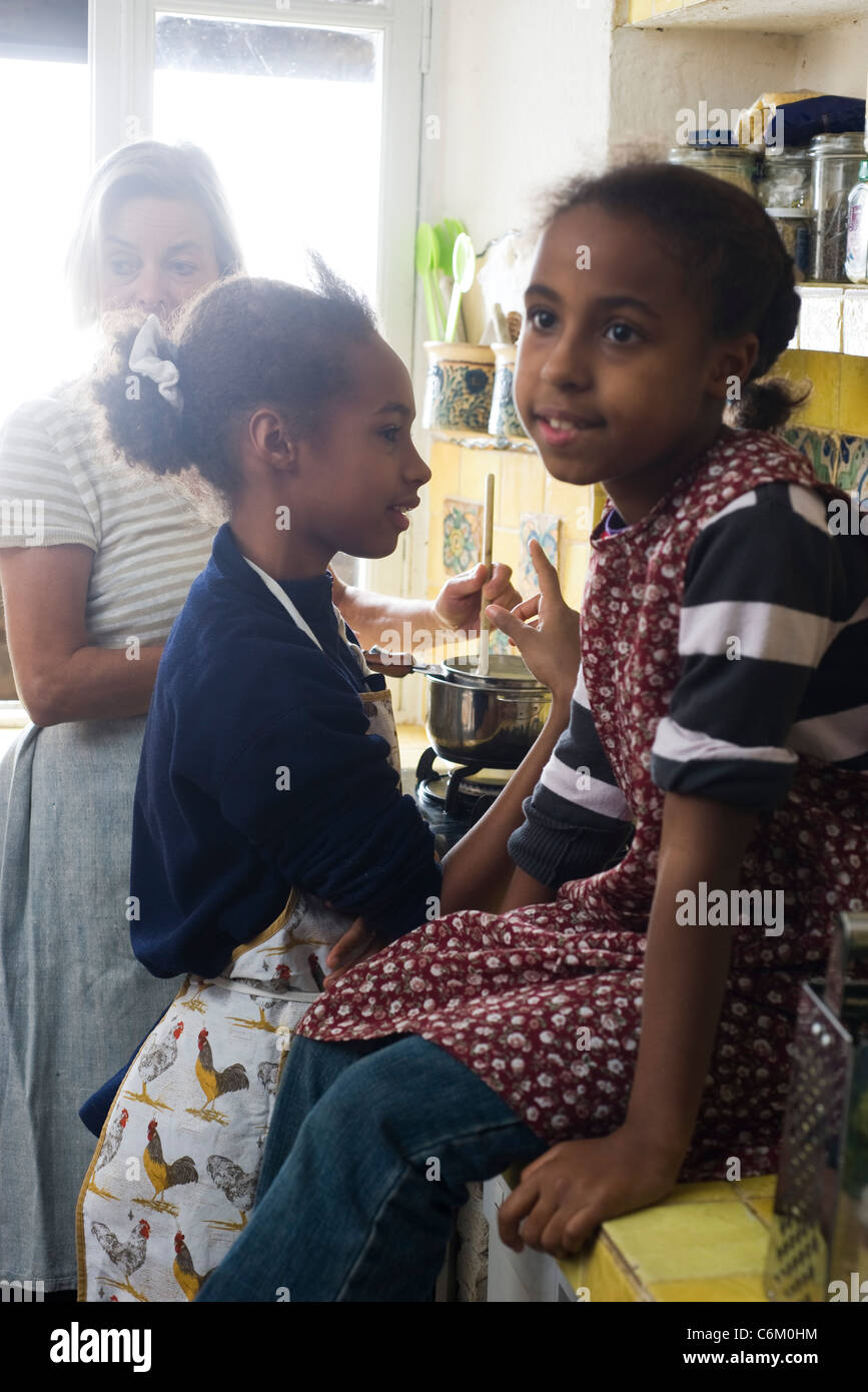 Grandmother with granddaughters cooking together in kitchen Stock Photo
