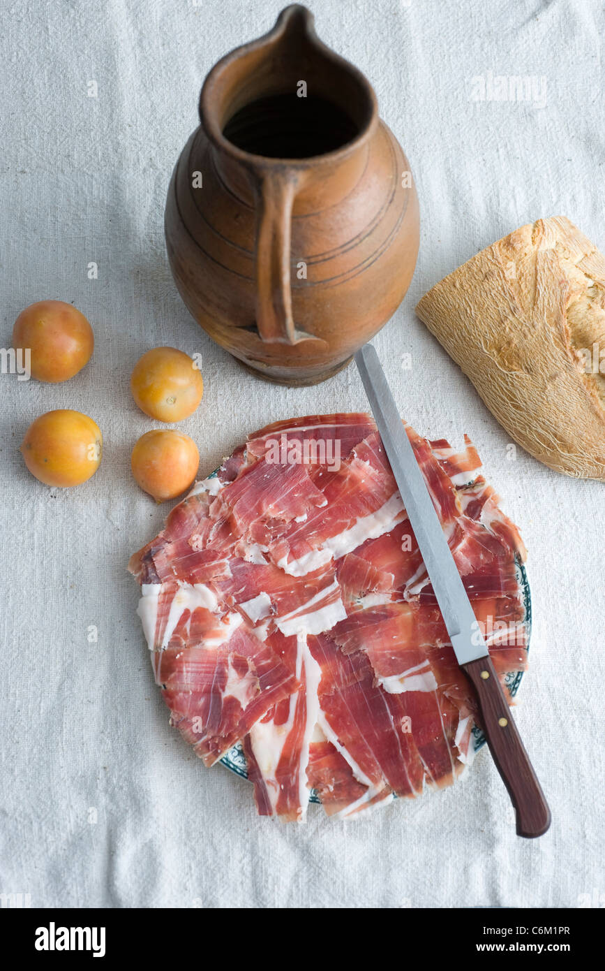 Plate of cut prosciutto with plum tomatoes and loaf of bread Stock