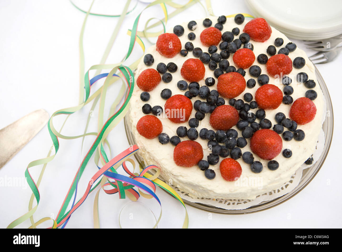 Strawberry blueberry cake surrounded by party streamers Stock Photo