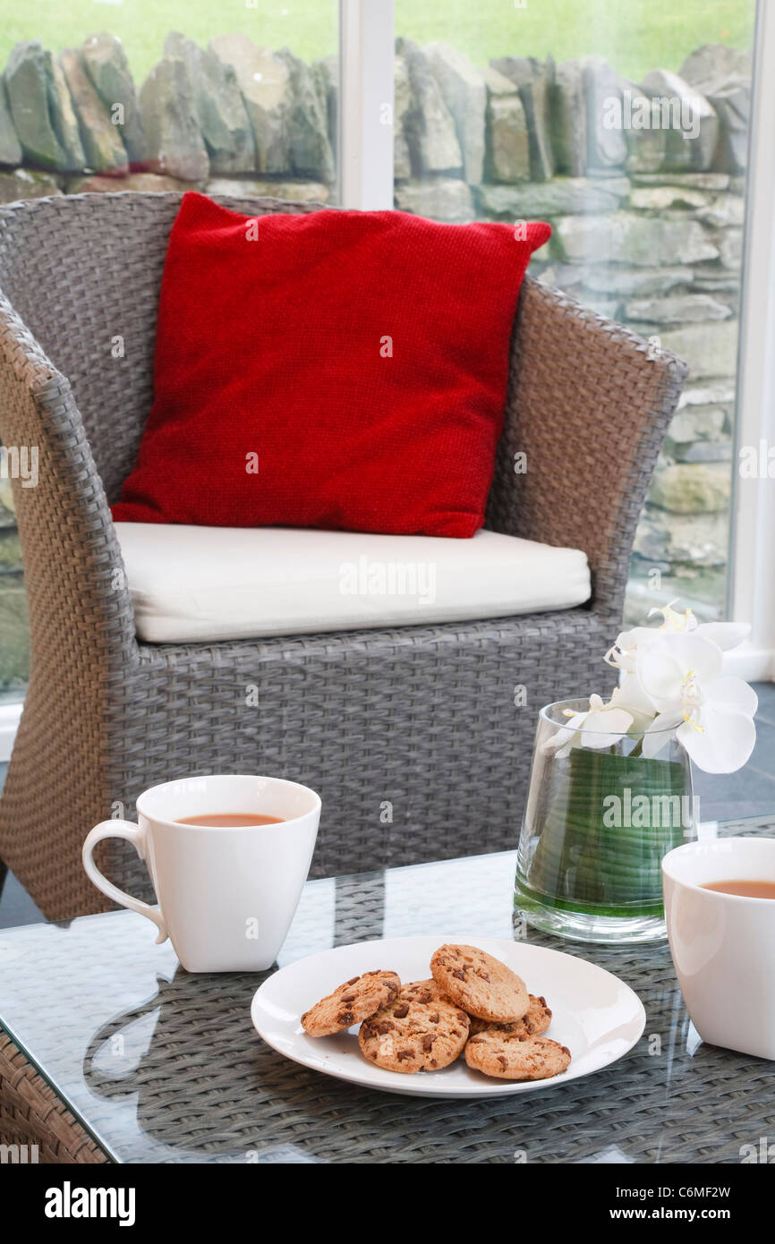 Coffee and cookies in a modern but cozy home interior with wicker furniture in a conservatory living room Stock Photo