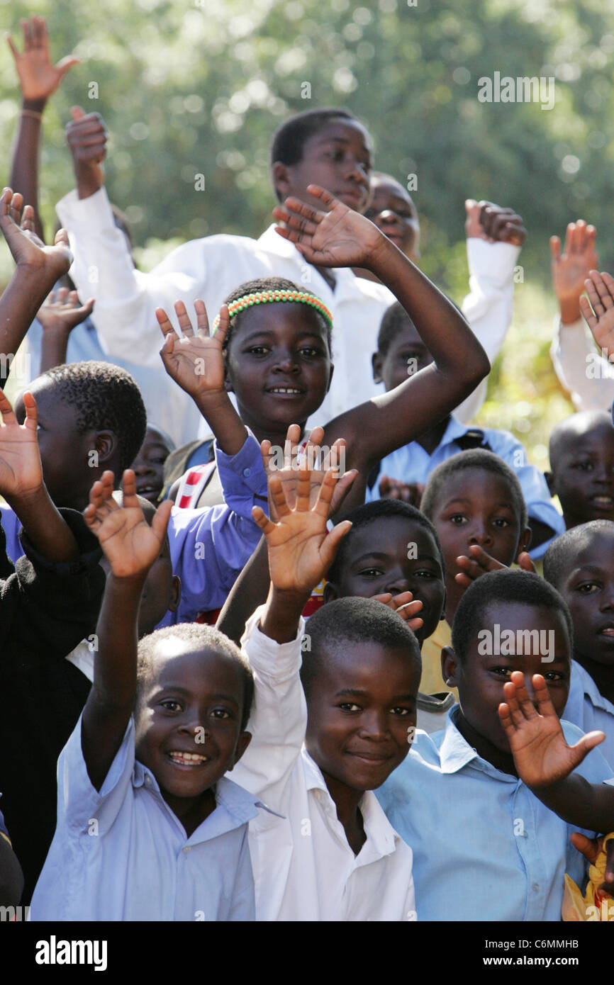 Group of smiling young school boys in an outdoor classroom waving Stock Photo