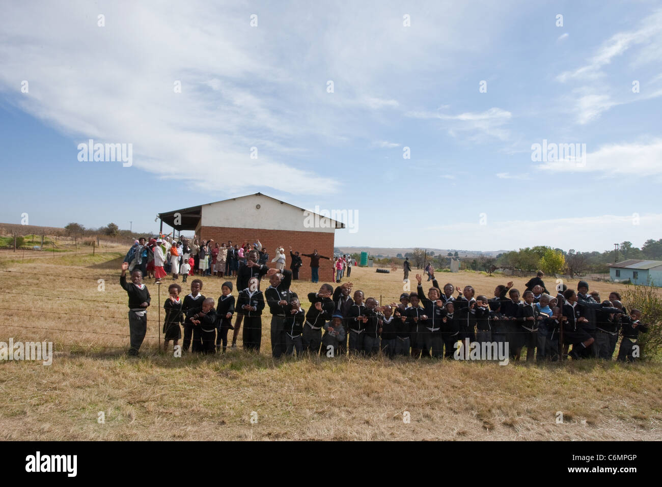 School children standing along the fence outside a rural school Stock Photo