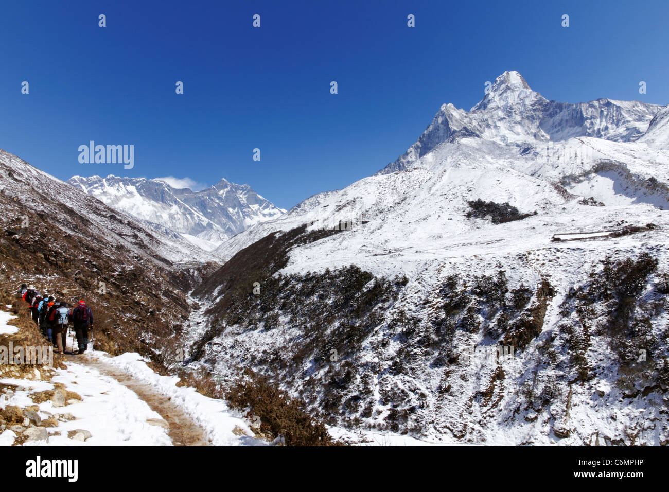 Trekkers walking towards Everest with Ama Dablam mountain on the right, Everest Region, Nepal Stock Photo