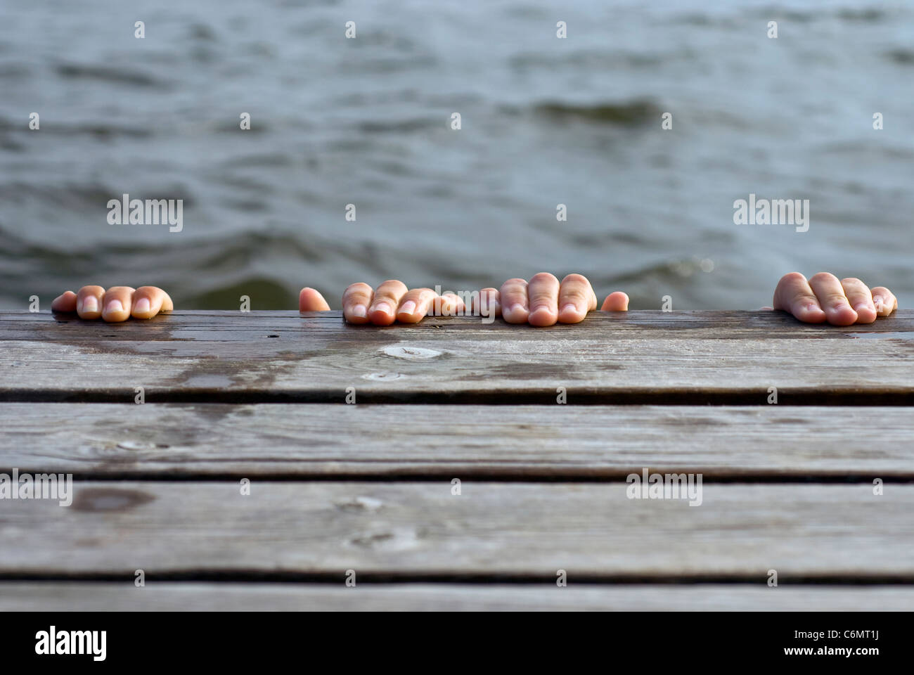 Young people playing on the swim platform, both hiding from the photographer Stock Photo