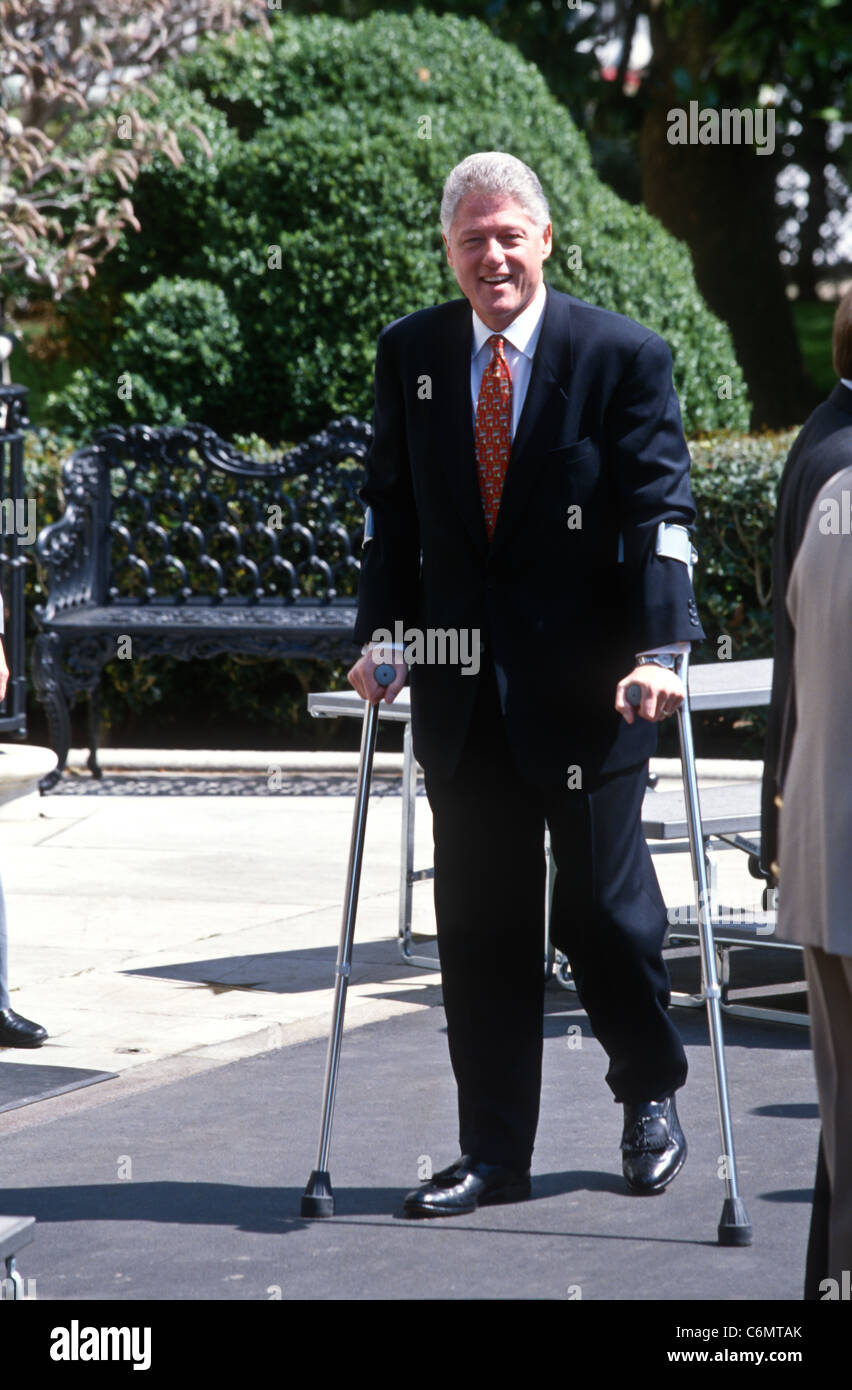 President Bill Clinton walks with crutches as he recovers from a knee injury at the White House April 3, 1997. Stock Photo