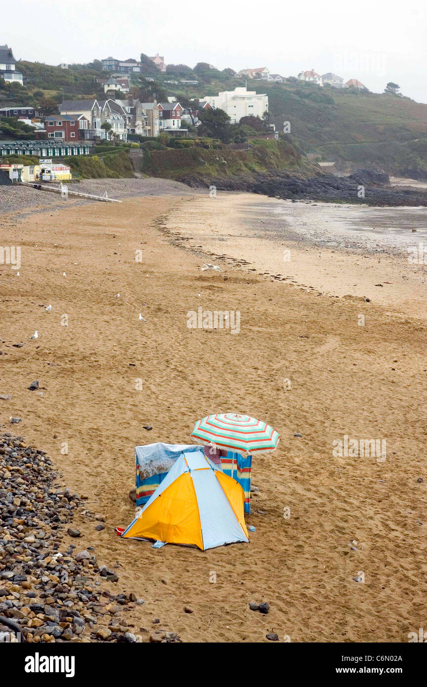 One lone determined holidaymaker builds a shelter to cover from the rain on the empty beach at Langland Bay near Swansea. Stock Photo