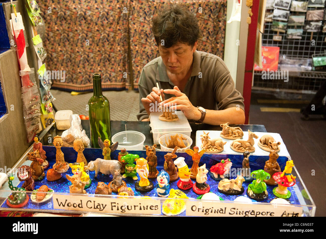 Chinese craftsman painting wood clay figurines, Chinatown market