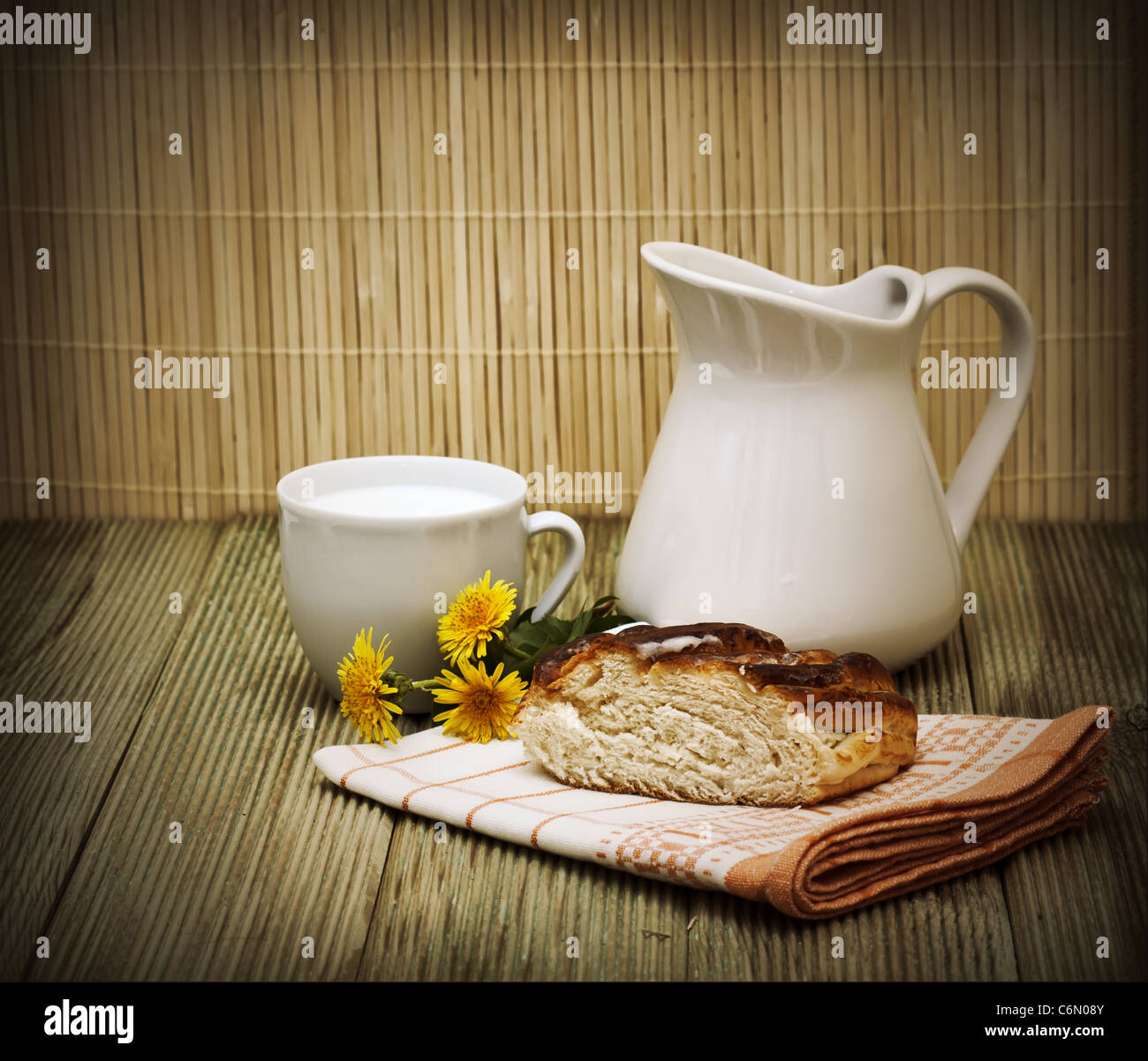 pitcher of milk and a piece of cake on a wooden table Stock Photo