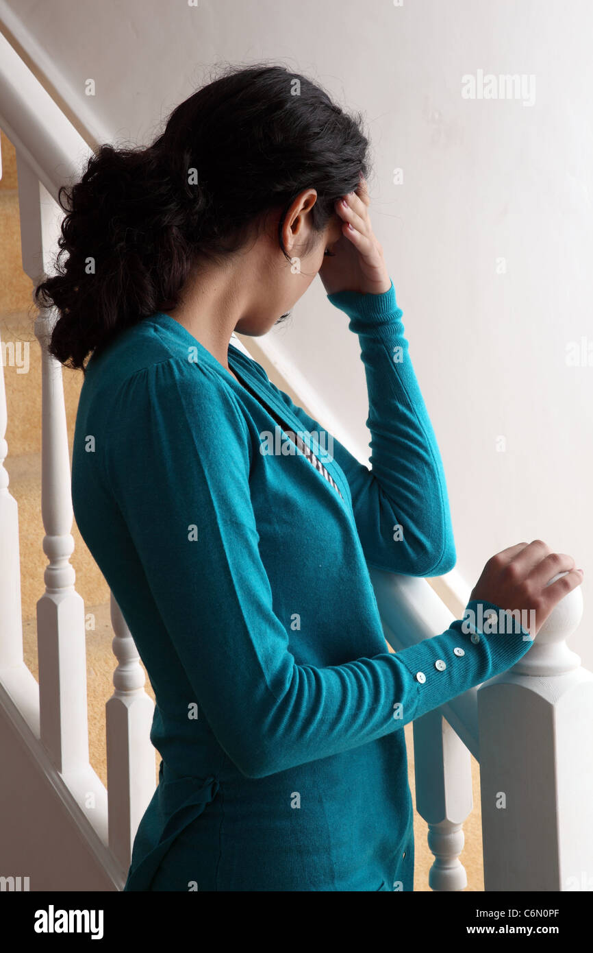 Woman back to camera by the stairs hand on face. Stock Photo