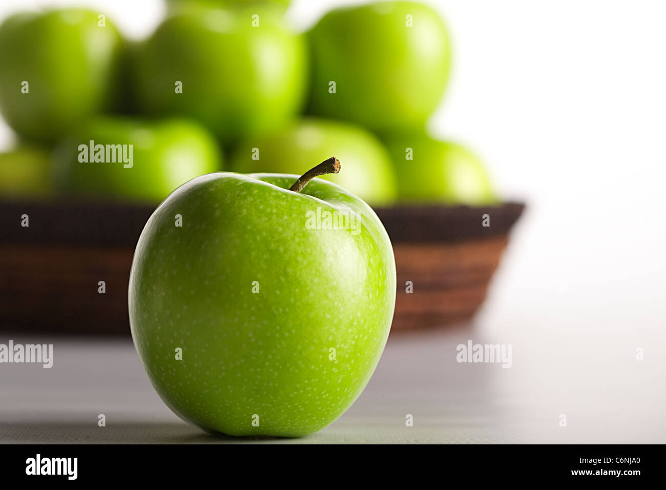 Green Apple detail with basket of apples in the background, shallow depth of field Stock Photo