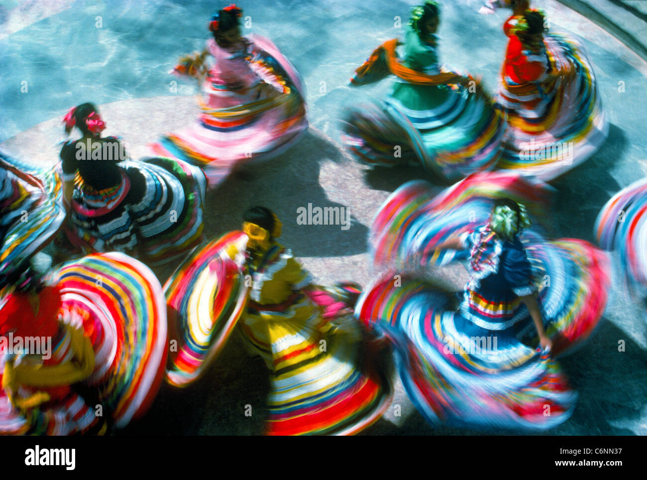An overhead view shows off the colorful traditional dresses of twirling folkloric dancers who often entertain tourists in Mexico, North America. Stock Photo