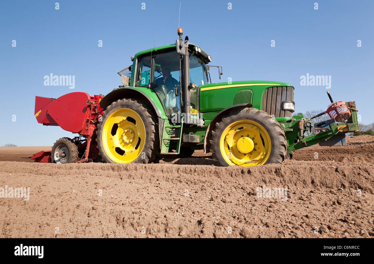 A n agricultural tractor with a potato planter fitted planting potatoes Stock Photo