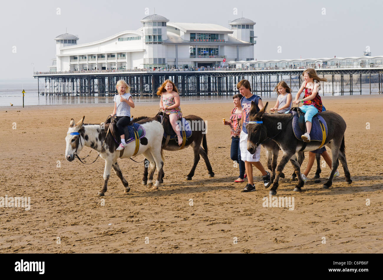 Children riding donkeys on the beach at the English seaside town of Weston Super Mare Stock Photo
