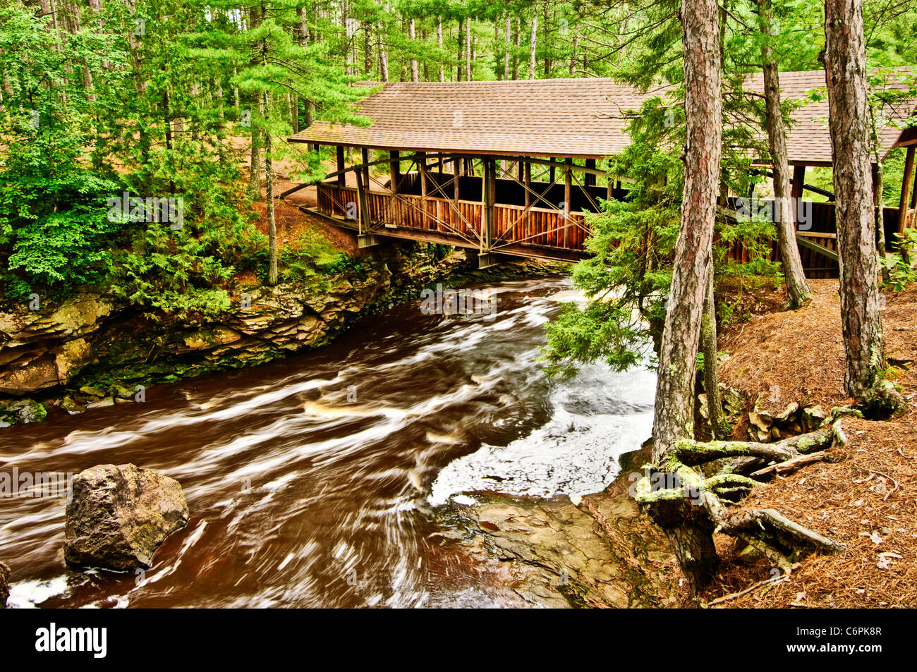 The Amnicon River flows under a covered bridge at Amnicon Falls State Park near Superior Wisconsin. Stock Photo