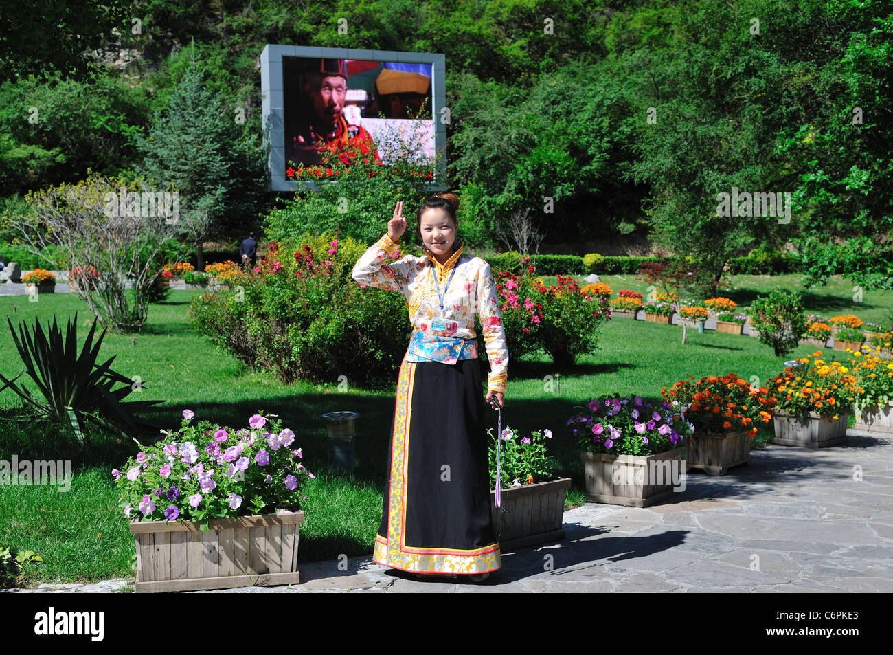 A young lady in Tibetan dress greets visitors in Jiuzhaigou Nature Reserve, an UNESCO World Heritage site. Sichuan, China. Stock Photo