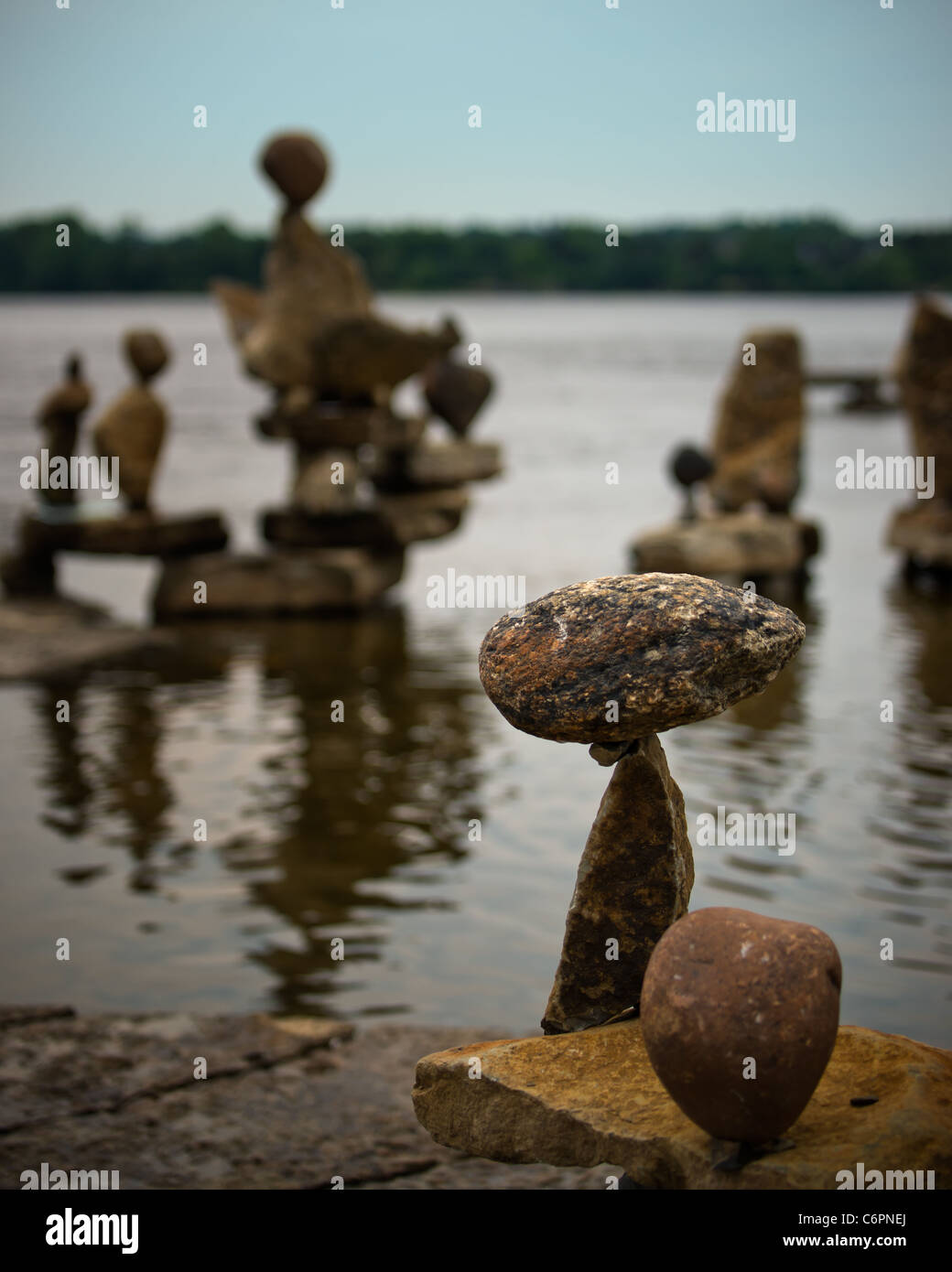 A small Inuksuk (inukshuk) stands in the foreground with many more out of foucs in the background. Stock Photo