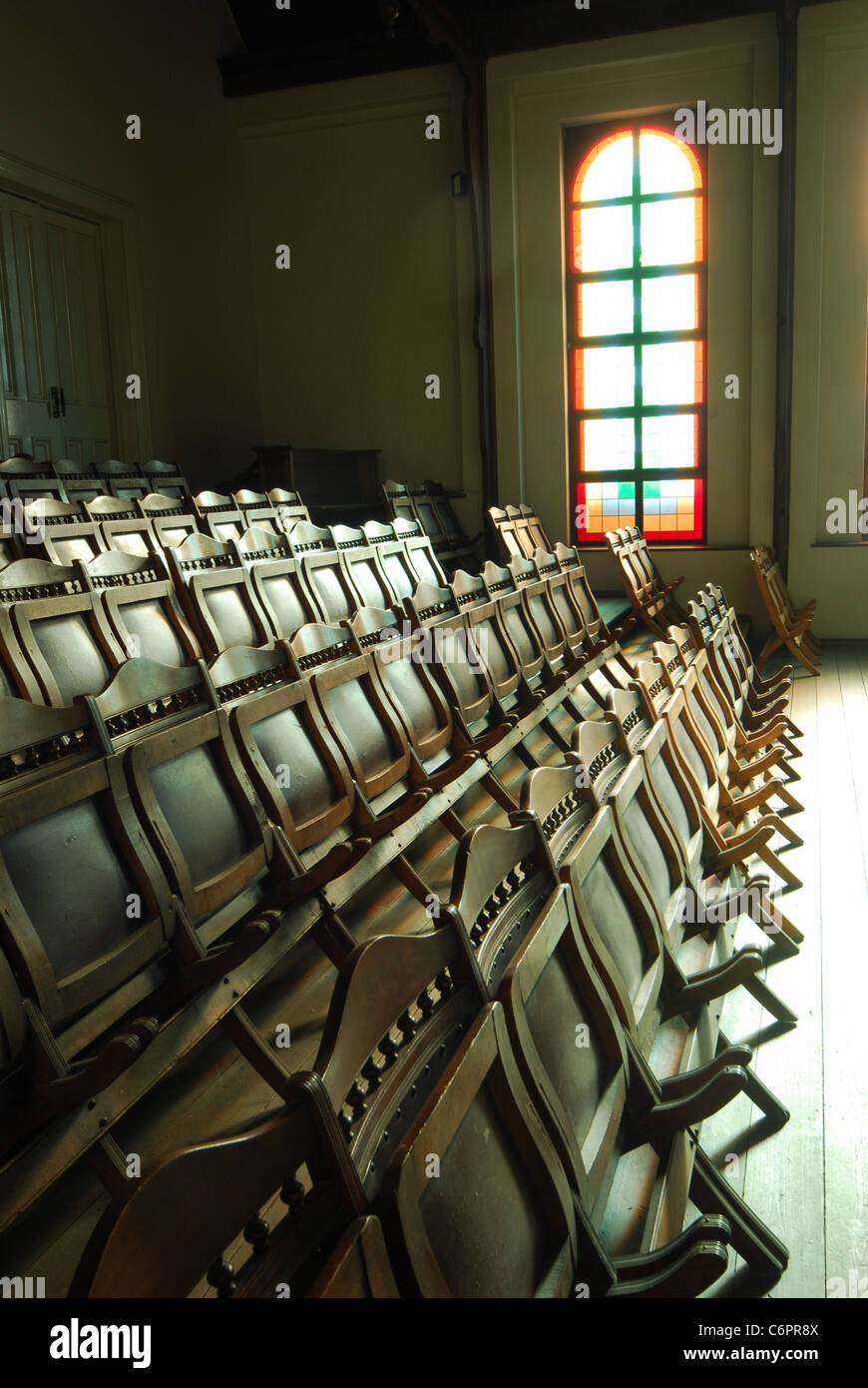 Stained glass church window and foldaway seats in an old church in Cape