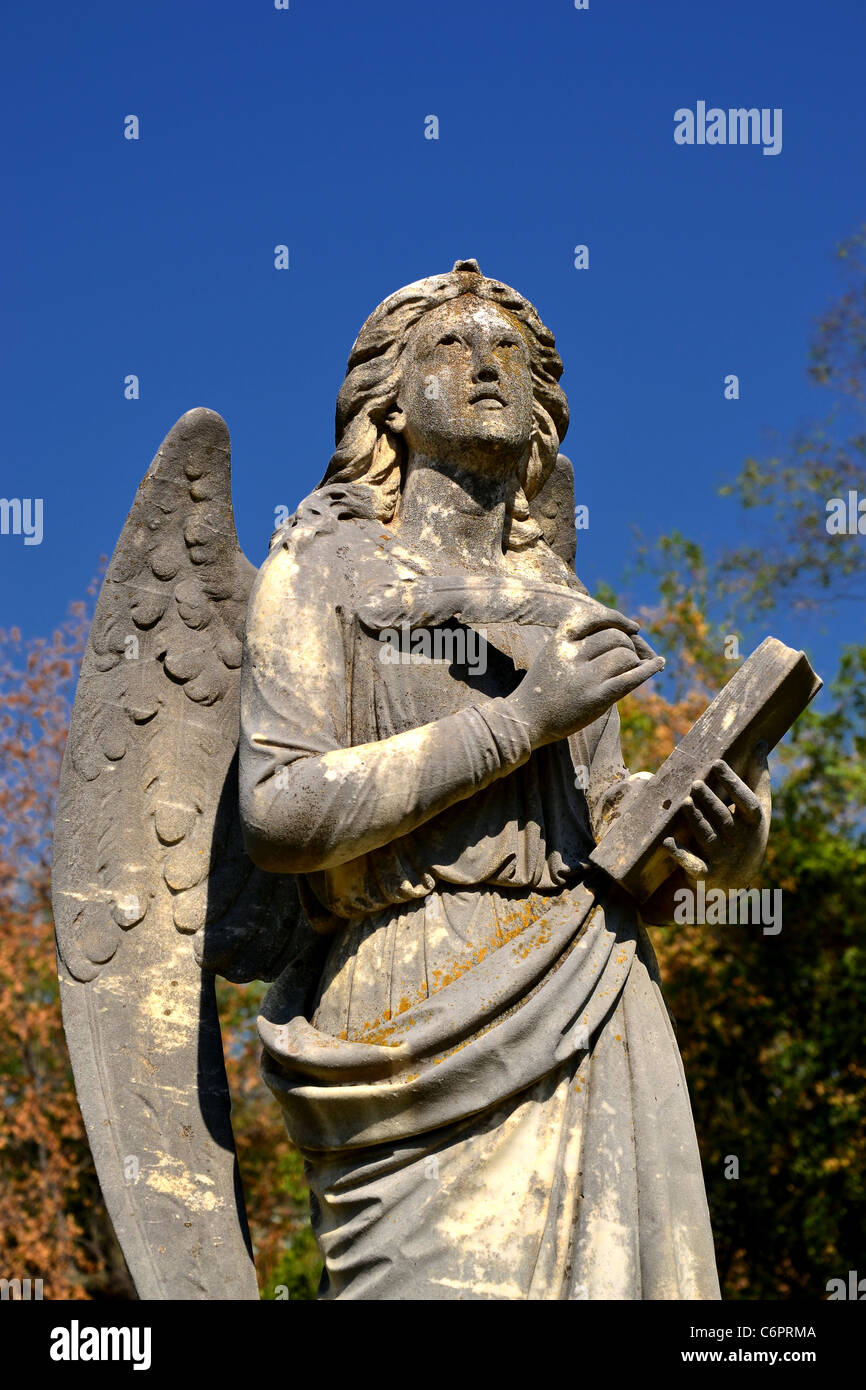 A image of a angel statue writing names down in the book of life Stock