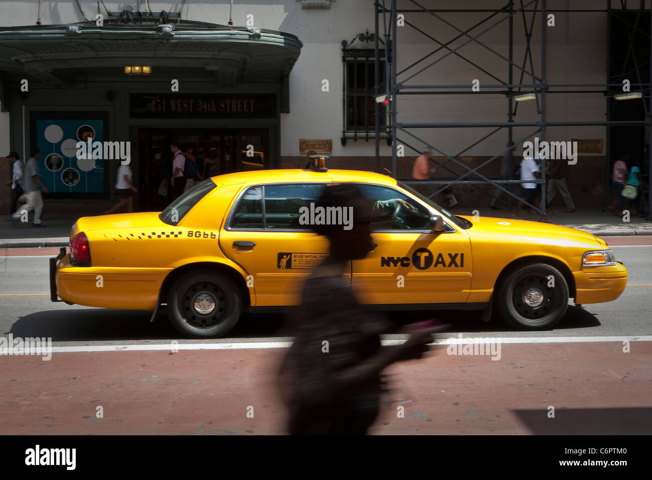 A woman walks by a NYC Taxi in the New York City borough of Manhattan, NY, Tuesday August 2, 2011. Stock Photo