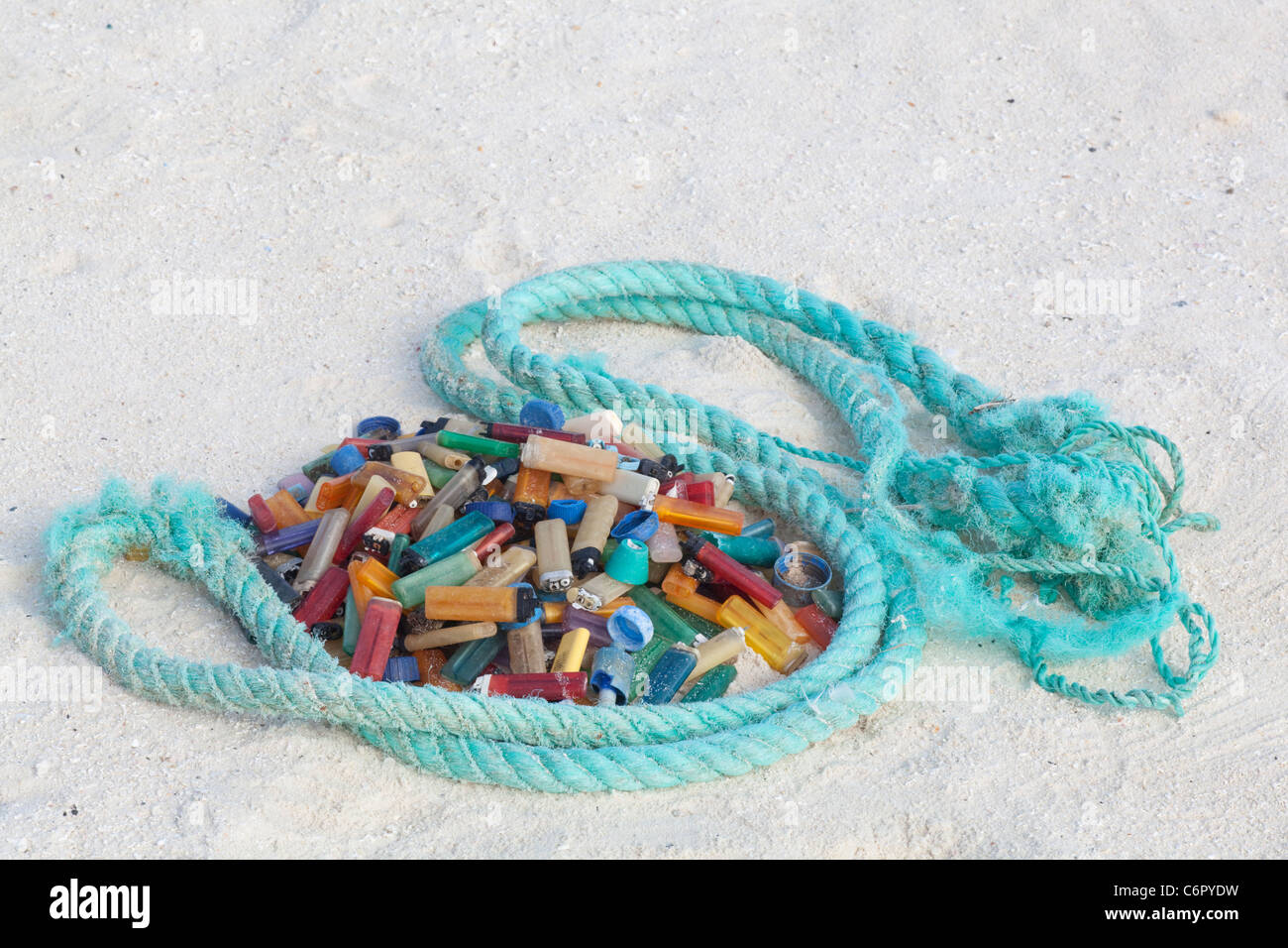 Cigarette lighters and rope, marine debris washed ashore on a pacific island then collected by tourists to prevent harm to seabirds or other wildlife Stock Photo