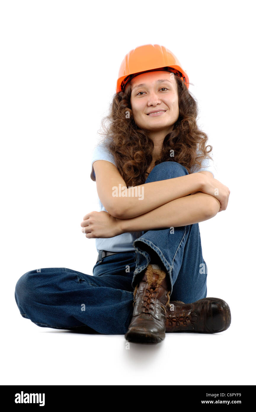 Pretty young woman in a hard hat sitting isolated on white background