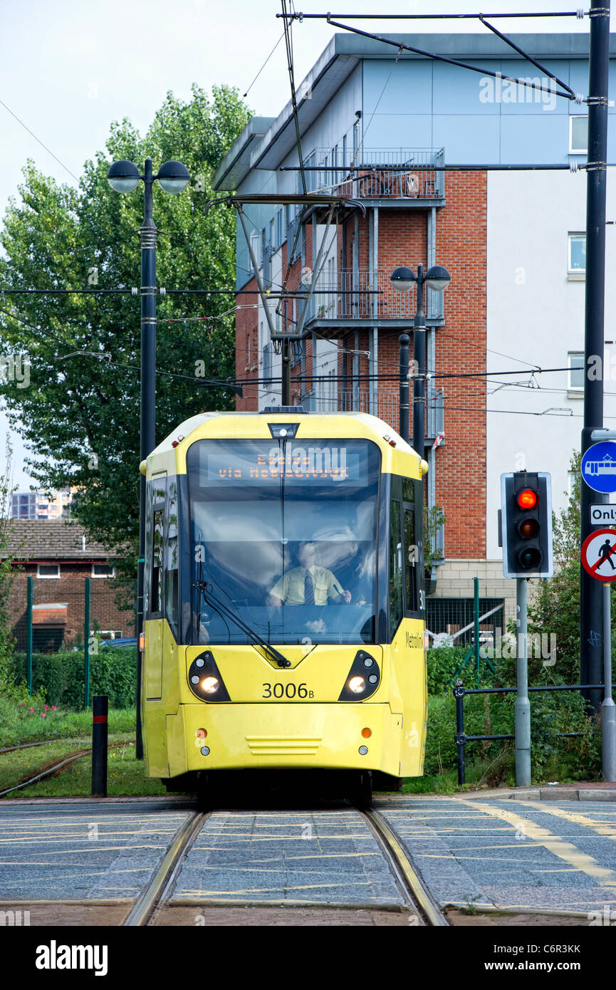 New yellow Metrolink tram crossing a road Stock Photo